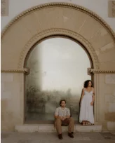 Couple posing under a stone arch during a romantic photoshoot in Barcelona.