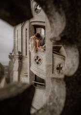 Couple kissing on a stone balcony, framed by ornate Barcelona architecture