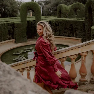 Woman in a flowing red dress during a portrait photoshoot in a garden in Barcelona