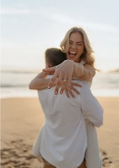 Joyful bride-to-be showing the ring toward the camera on a Barcelona beach