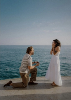 Seaside surprise proposal in Barcelona with partner kneeling and the ocean behind