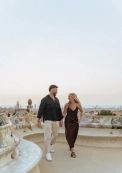 Couple walking hand in hand on mosaic terrace of Park Güell with panoramic view of Barcelona