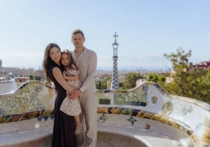 Family portrait with parents and daughter on mosaic bench in Park Güell, Barcelona.