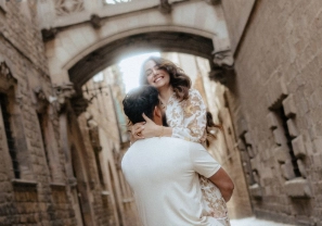 Man lifting his smiling partner beneath Gothic arches in Barcelona’s historic quarter.