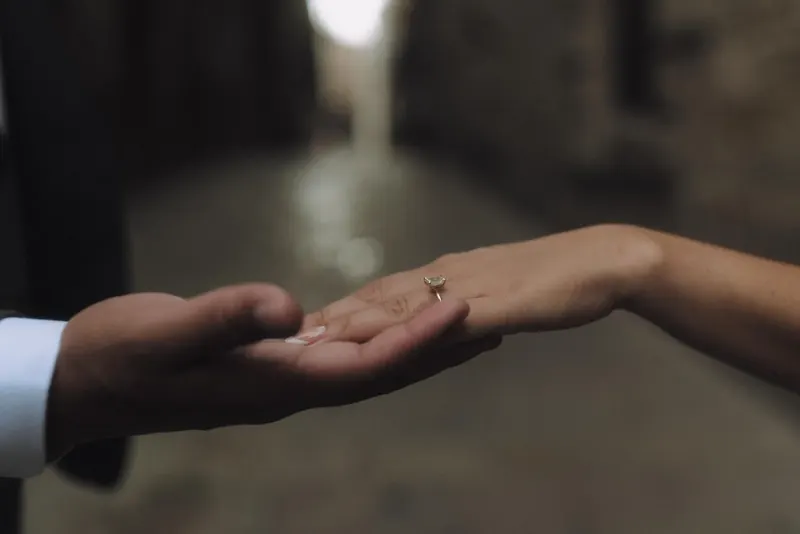A close-up of Ashley and Edgar holding hands with Ashley's ring in focus.