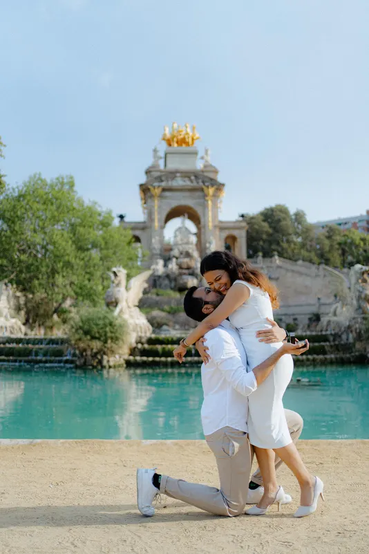 A couple celebrates their engagement with a joyful embrace by the fountain at Parc de la Ciutadella during a proposal shoot.