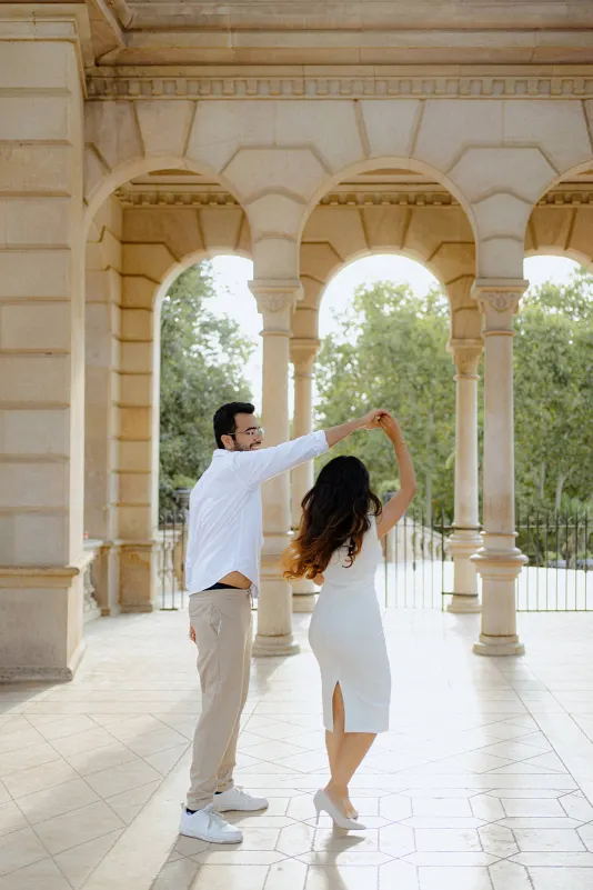 A couple dances joyfully under elegant stone arches during their surprise proposal photoshoot at Parc de la Ciutadella.