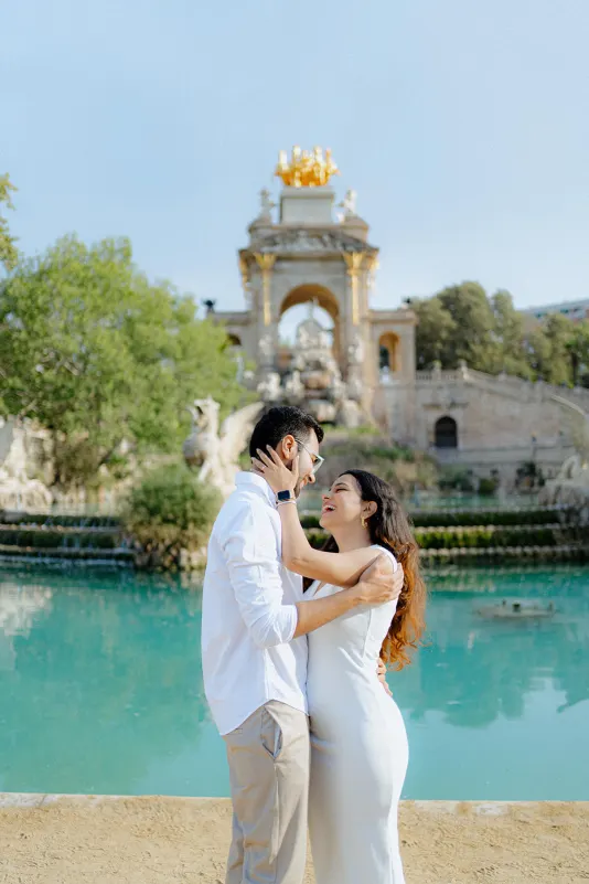 A couple embraces and laughs by the fountain at Parc de la Ciutadella during a surprise proposal photoshoot.