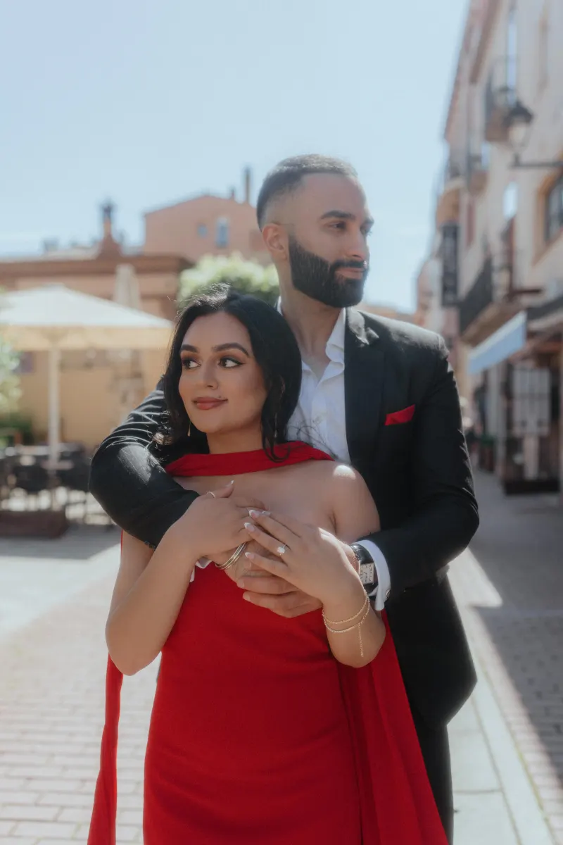 A couple embraces in a sunlit Begur street, capturing a romantic moment from their surprise proposal photoshoot.