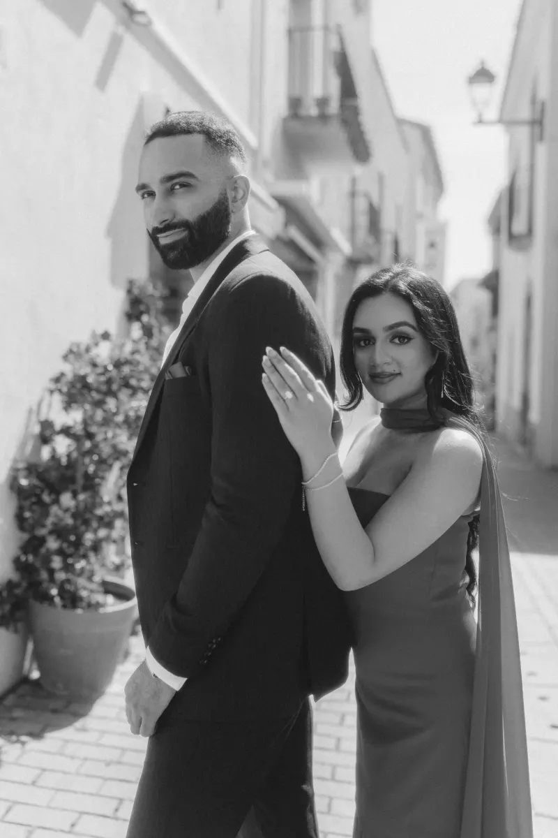 A couple embraces in a sunlit Begur street, celebrating their engagement during a surprise proposal photoshoot.