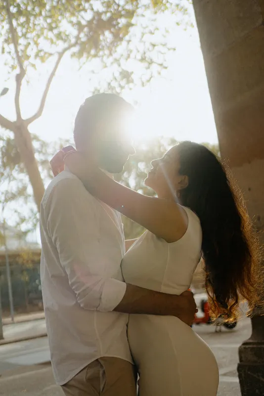 A couple embraces in golden sunlight during a surprise proposal photoshoot on a charming city street.