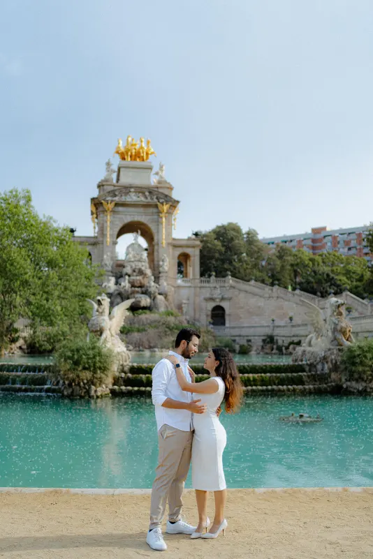 A couple gazes lovingly at each other by the fountain during a surprise proposal photoshoot at Barcelona’s Parc de la Ciutade