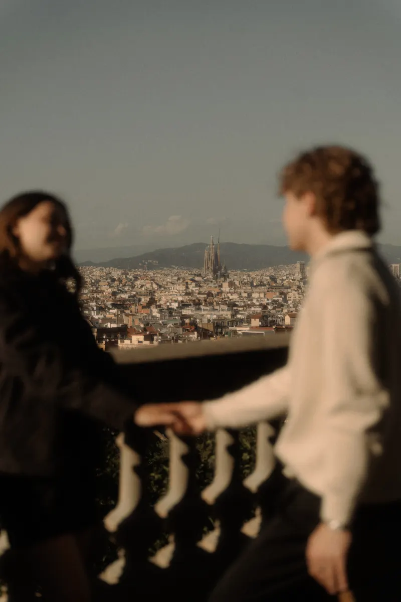 A couple holds hands on a terrace with Barcelona’s skyline behind them, captured during a couples & engagements session.
