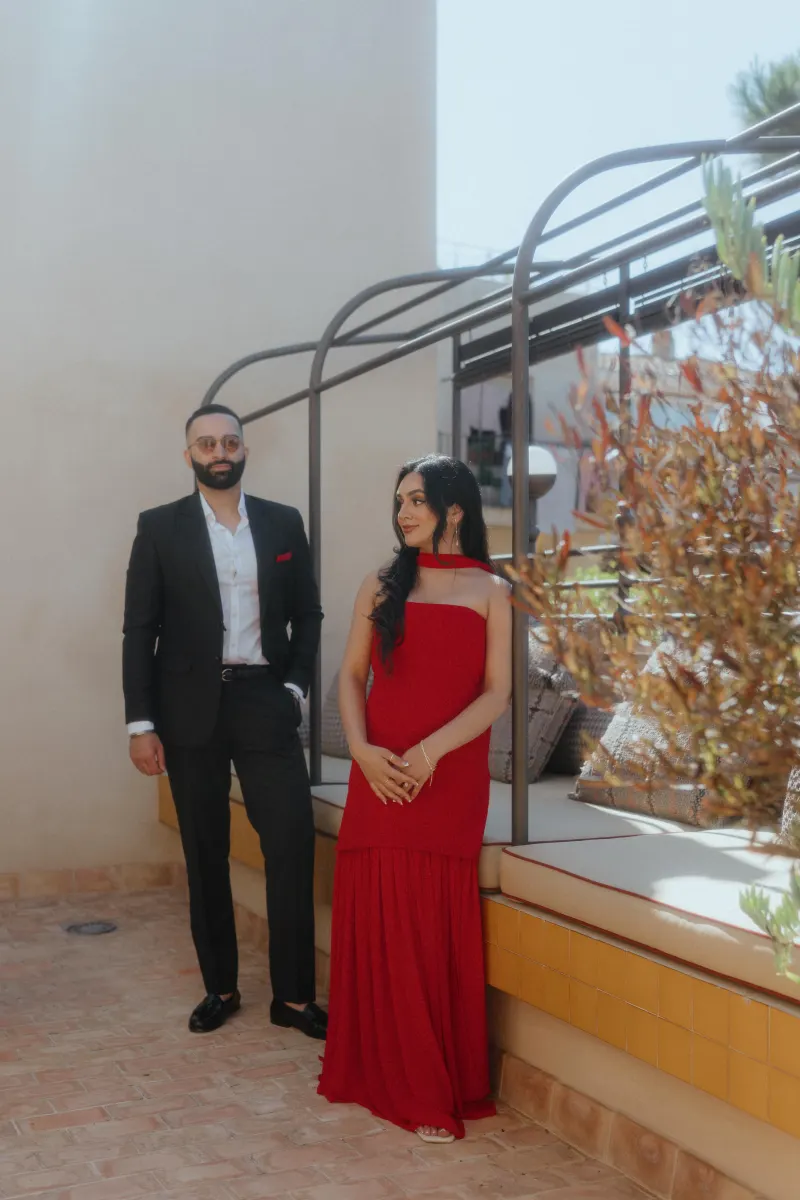 A couple in elegant attire shares a quiet, anticipatory moment on a sunlit patio during their surprise proposal shoot.