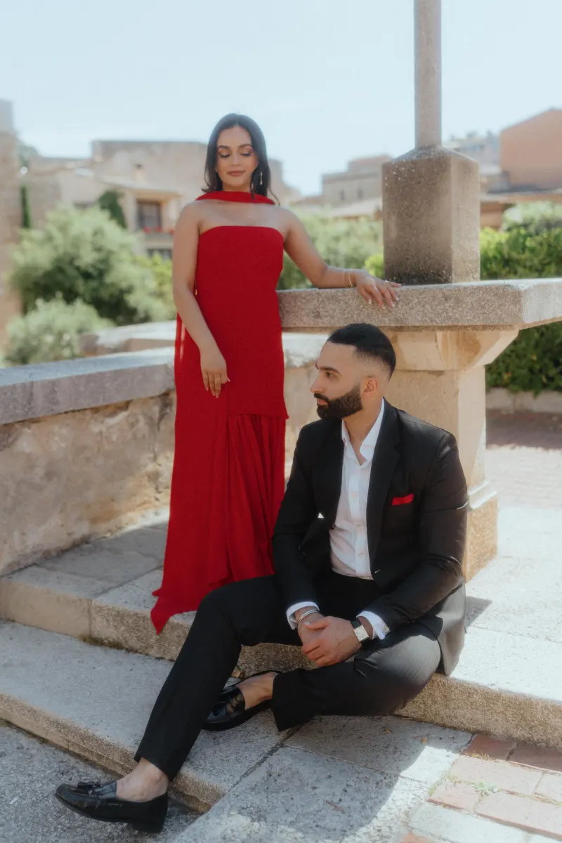 A couple in formal attire share a tender moment by a stone monument in Begur during their surprise proposal session.