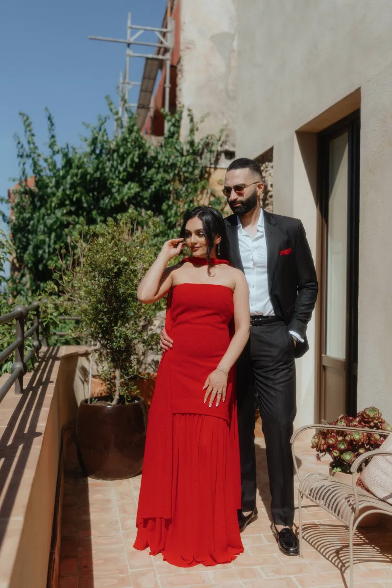 A couple in formal attire stands close together on a sunlit terrace, captured during their surprise proposal session.