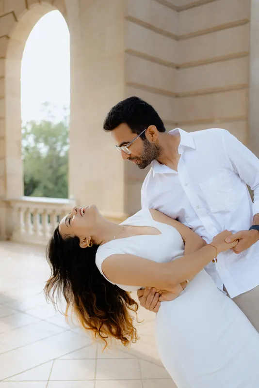 A couple shares a joyful dance and laughter beneath elegant arches during their surprise proposal photoshoot in Barcelona.
