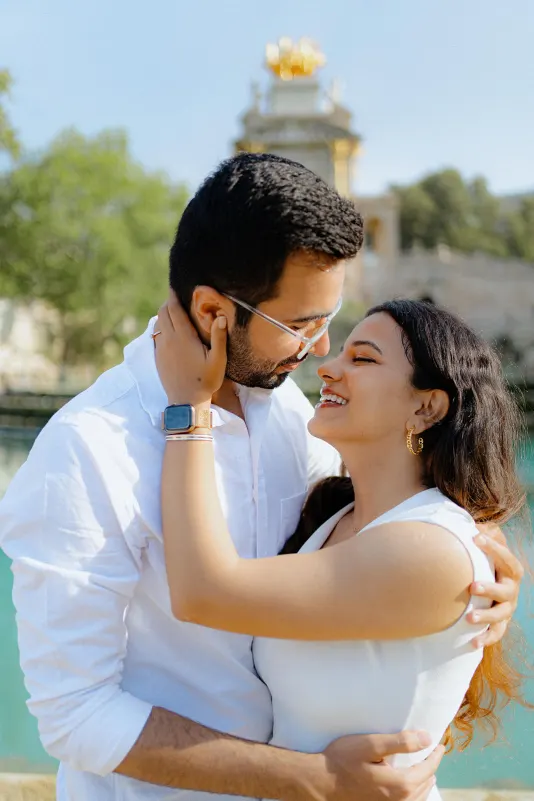 A couple shares a joyful embrace and smiles at each other during a surprise proposal photoshoot at Parc de la Ciutadella.