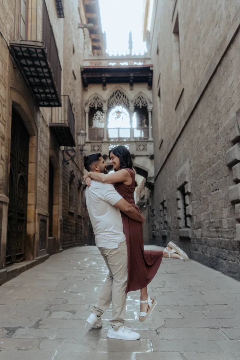 A couple shares a joyful embrace in a historic European alley during their couples & engagements photoshoot.