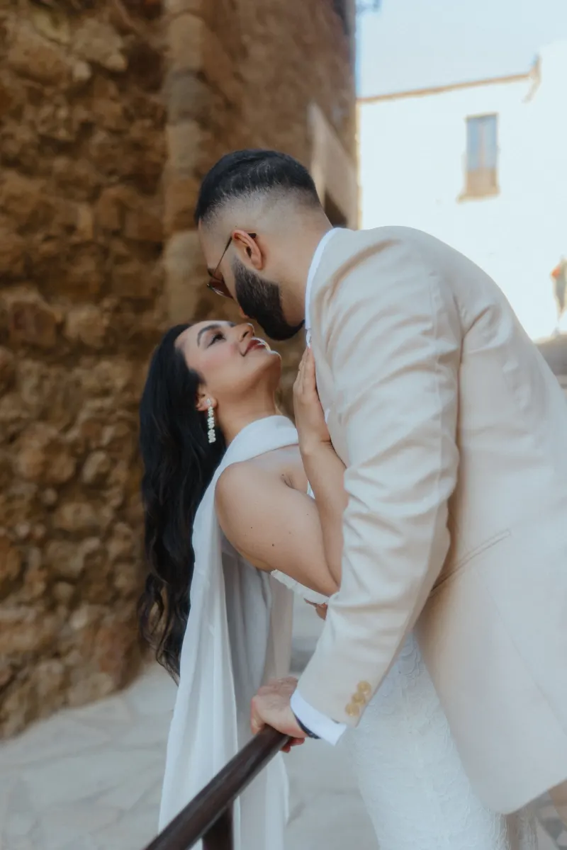 A couple shares a joyful embrace on a sunlit stone staircase during their surprise proposal photoshoot.
