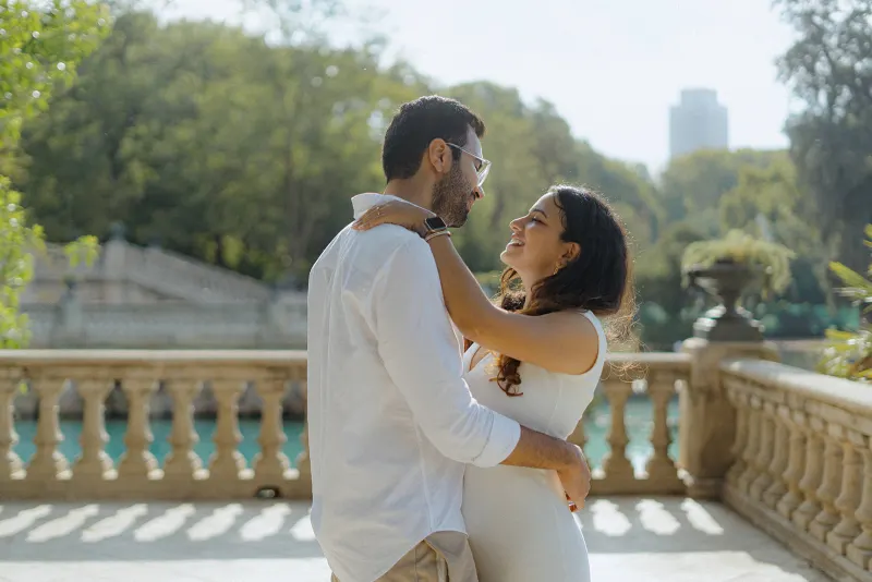 A couple shares a joyful embrace on a sunlit terrace at Parc de la Ciutadella during a surprise proposal photoshoot.