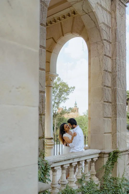 A couple shares a joyful embrace on a vine-covered terrace during their surprise proposal photoshoot in Parc de la Ciutadella