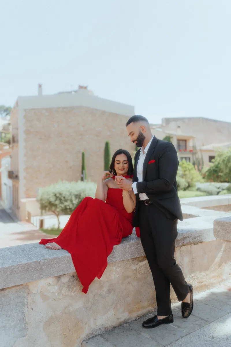 A couple shares a joyful moment on a stone terrace in Begur, celebrating their surprise proposal photoshoot.