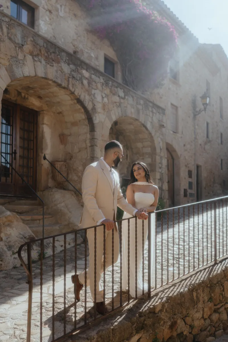 A couple shares a joyful moment on a sunlit stone walkway during their surprise proposal photoshoot.