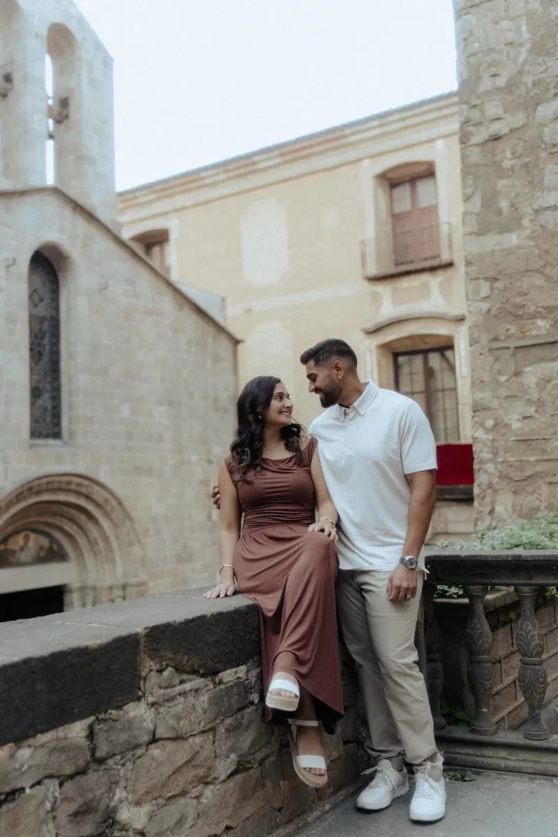 A couple shares a loving gaze in a historic courtyard during their couples & engagements photoshoot.