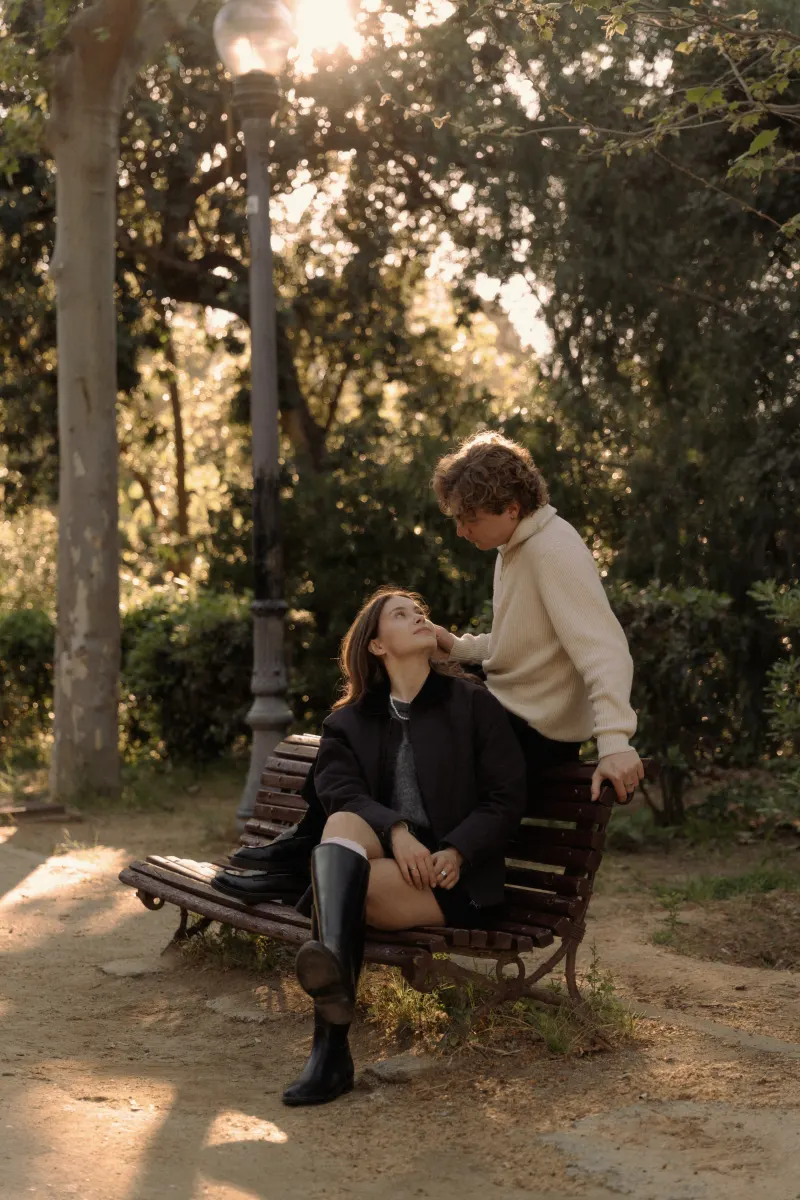 A couple shares a loving gaze on a park bench in Barcelona, captured during a couples & engagements photoshoot.