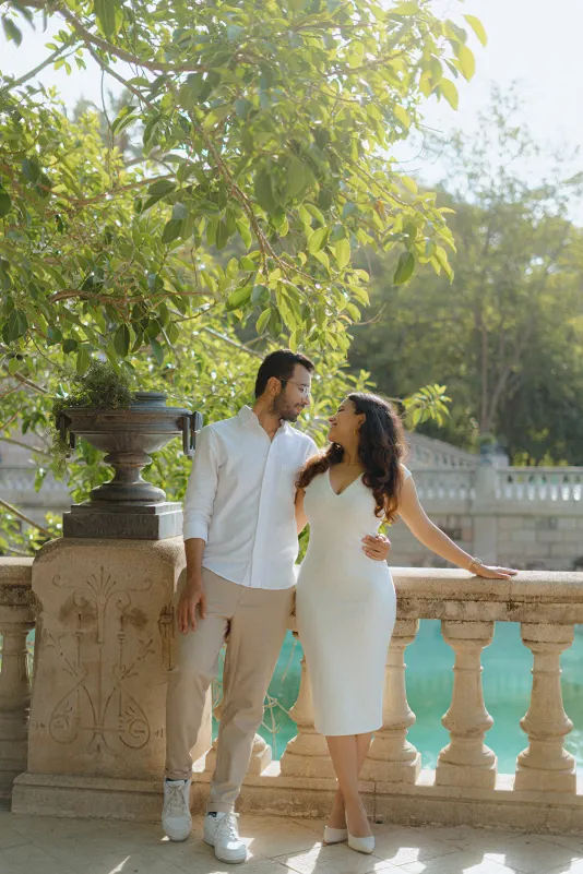 A couple shares a loving gaze on a sunlit terrace by the water during their surprise proposal photoshoot in Barcelona.