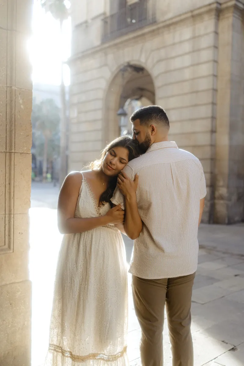 A couple shares a peaceful embrace in soft sunlight during a couples & engagements photoshoot in a historic city archway.