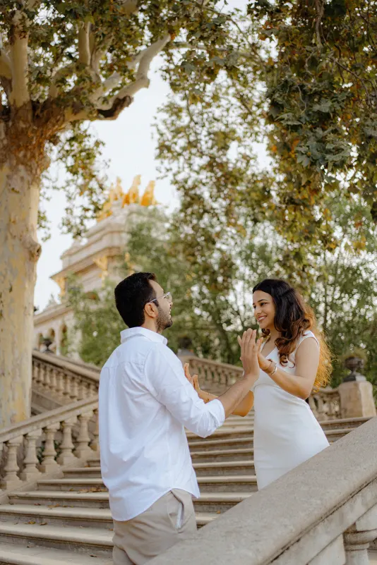 A couple shares a playful, heartfelt moment on the steps at Parc de la Ciutadella during a surprise proposal photoshoot.