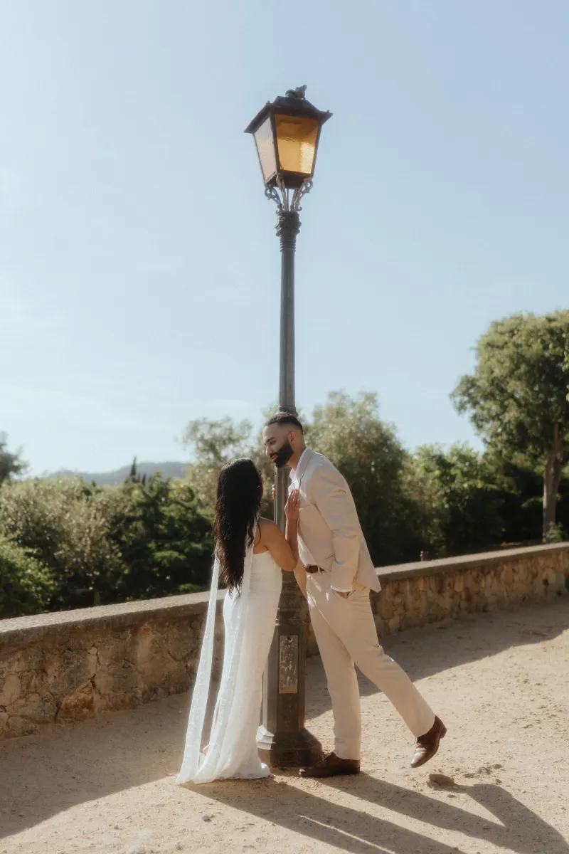 A couple shares a playful, romantic moment by a vintage lamppost during their surprise proposal photoshoot.