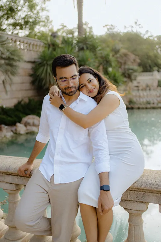 A couple shares a quiet, affectionate moment by the water during a surprise proposal photoshoot at Parc de la Ciutadella.