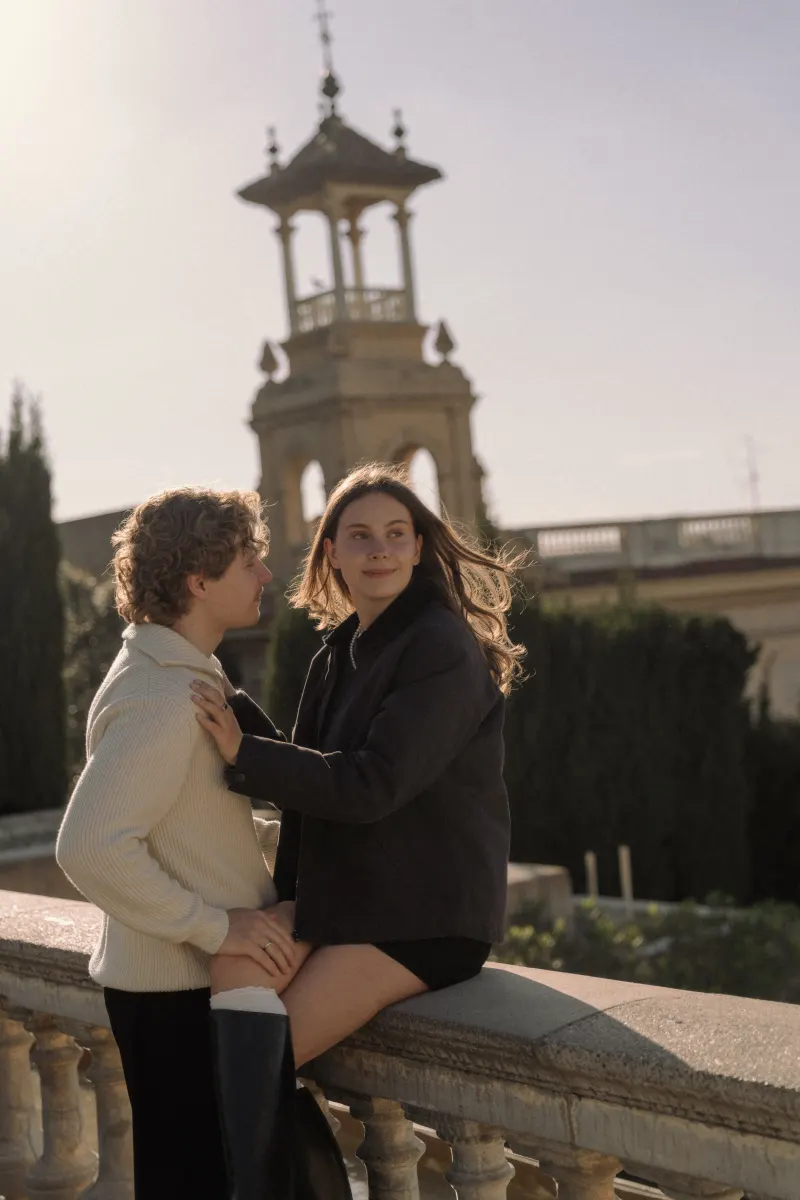 A couple shares a quiet, affectionate moment on a sunlit terrace in Barcelona during an engagement photoshoot.