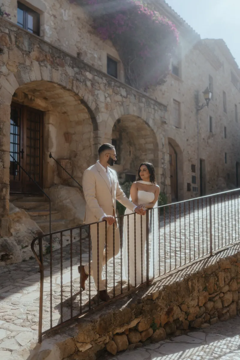 A couple shares a quiet, joyful moment on a sunlit stone walkway during their surprise proposal photoshoot.