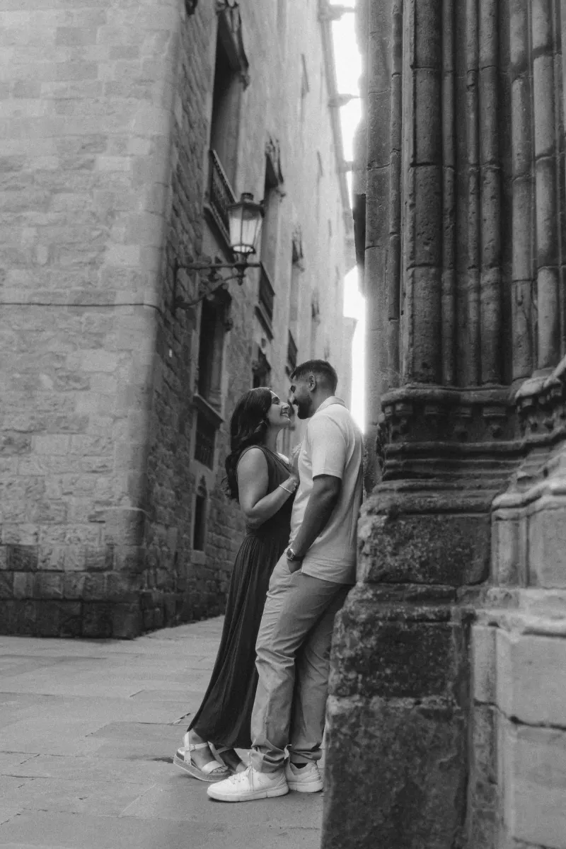 A couple shares a romantic, candid moment in a historic stone alley during their couples & engagements photoshoot.