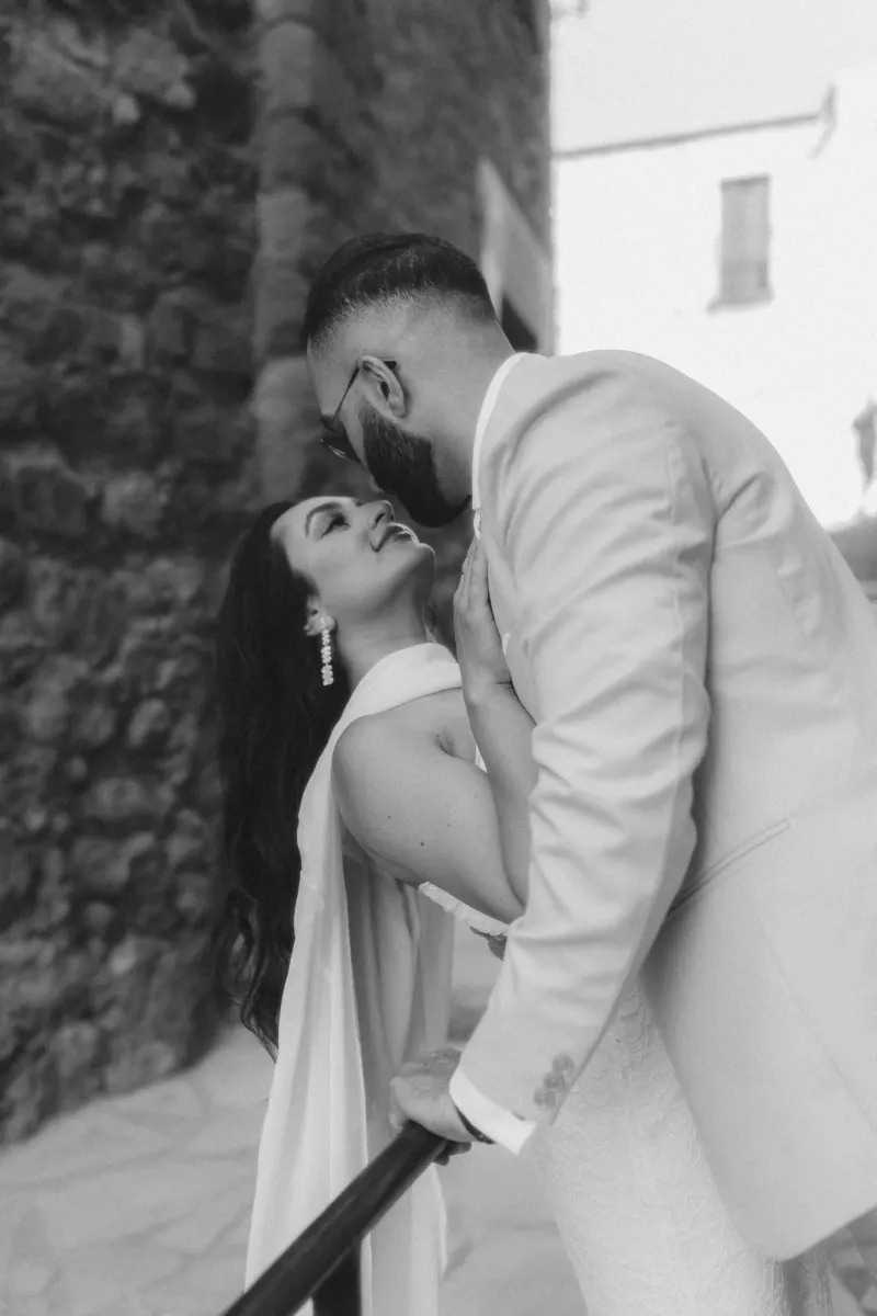 A couple shares a romantic, laughter-filled moment on a stone staircase during their surprise proposal photoshoot.