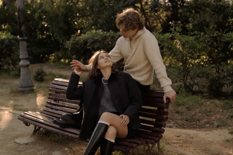 A couple shares a soft, affectionate gaze on a park bench in Barcelona during a couples & engagements photoshoot.