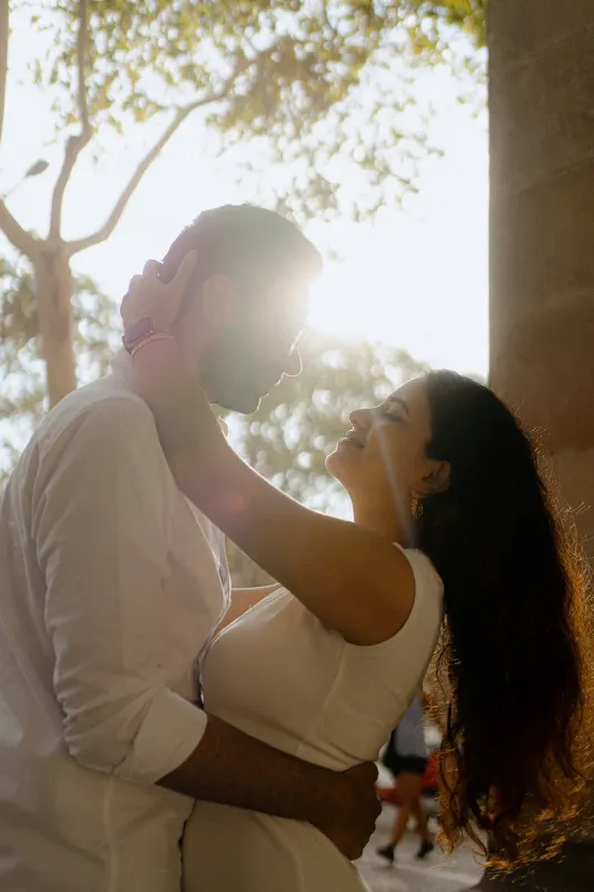 A couple shares a tender embrace in golden sunlight during a surprise proposal photoshoot in the city.