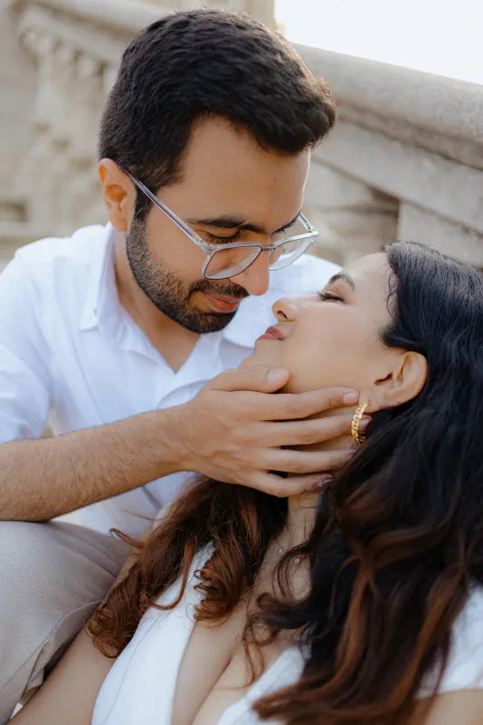 A couple shares a tender, loving gaze on stone steps during their surprise proposal photoshoot in Barcelona.