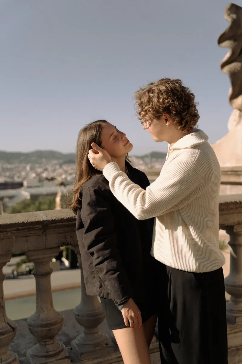 A couple shares a tender moment on a sunlit terrace in Barcelona during an engagement photoshoot.