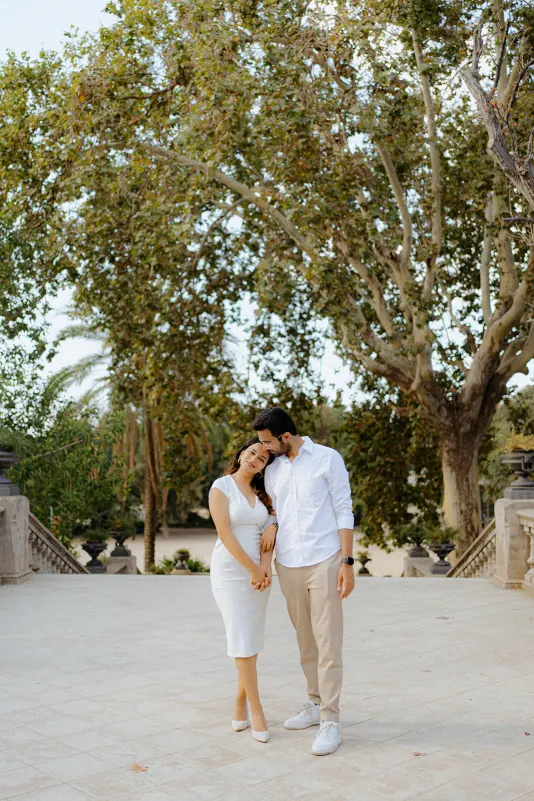 A couple shares a tender moment, smiling and holding hands during a surprise proposal photoshoot at Parc de la Ciutadella.