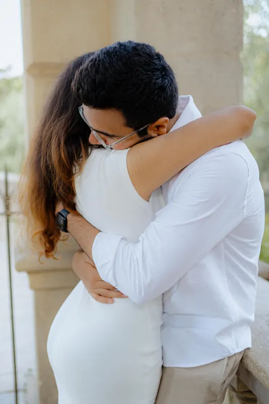 A couple shares an emotional embrace on a sunlit terrace during their surprise proposal photoshoot in Barcelona.