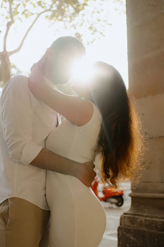 A couple shares an intimate embrace at sunset during a surprise proposal photoshoot in a historic city archway.
