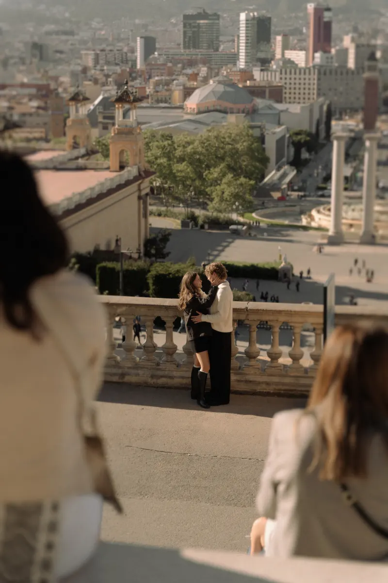 A couple shares an intimate moment during an engagement photoshoot overlooking the city from a scenic terrace.