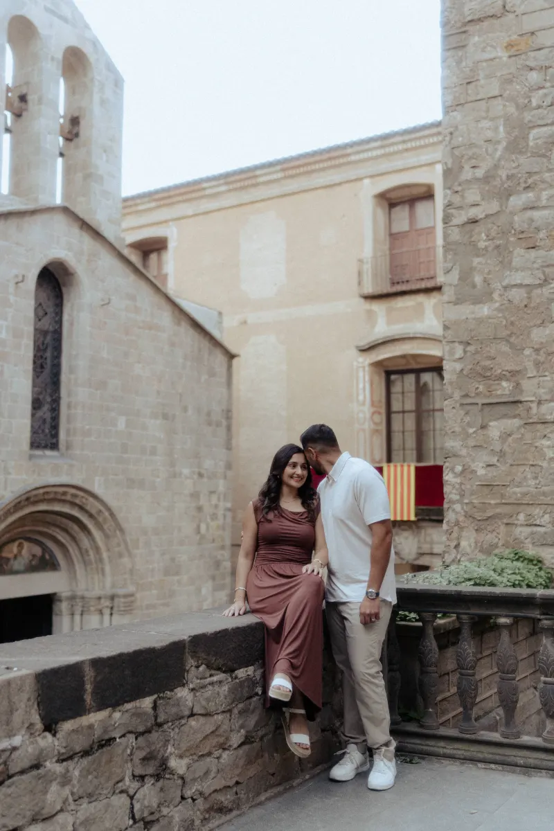 A couple shares an intimate moment on a stone terrace during their couples & engagements photoshoot in a historic courtyard.