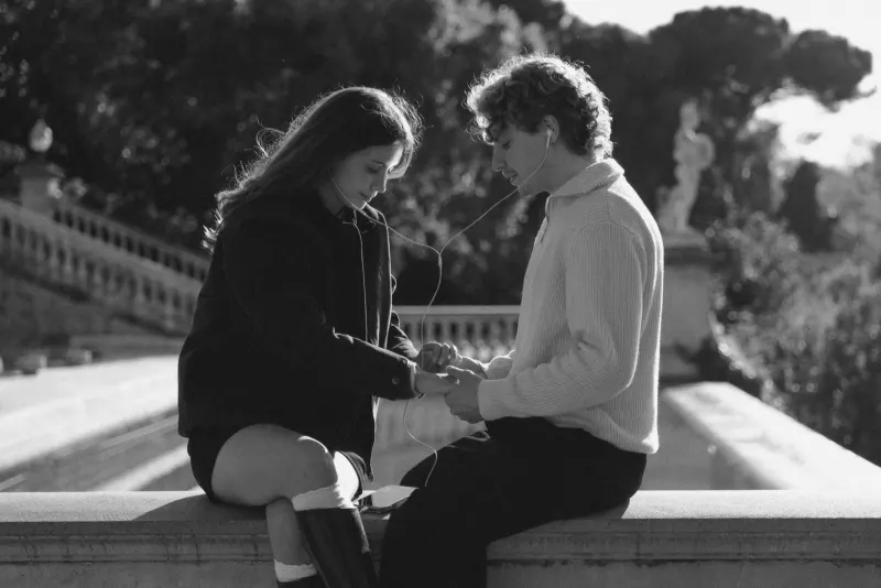 A couple shares headphones and a gentle touch on a sunlit terrace in Barcelona during a couples & engagements shoot.