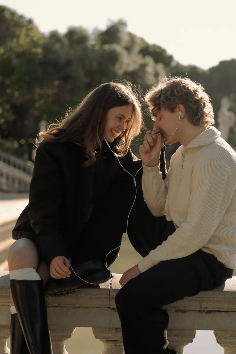 A couple shares headphones and a laugh on a sunlit terrace in Barcelona during a couples & engagements photoshoot.